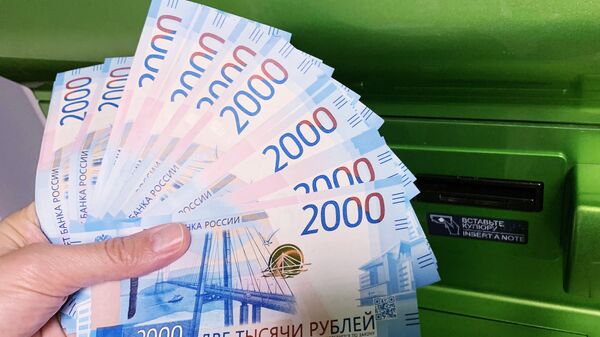 Клиент Сбербанка вносит наличные деньги в банкомат